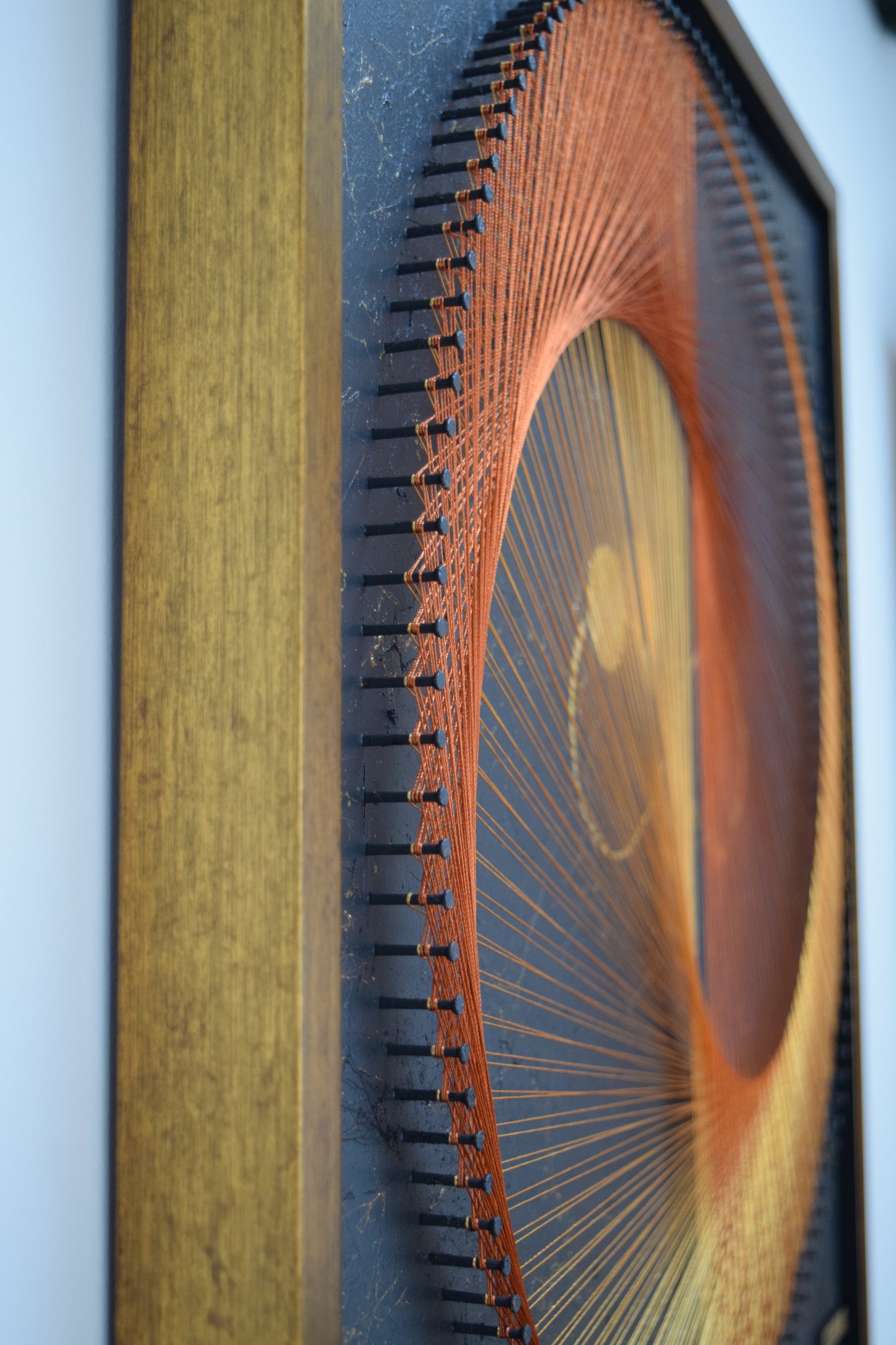 Side profile shot of string art showing perfectly aligned thread work over precision-nailed base.