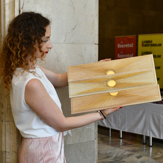 String artist holding the Sun Phases artwork set – handmade string art with gold leaf, shiny gold thread, and golden nails on pine and poplar wood.